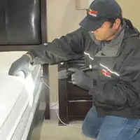Bed bug inspection technician checking a mattress and bed frame for signs of infestation in Seattle, WA
