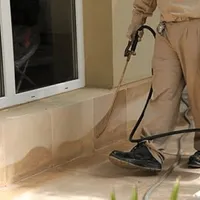 General pest control technician spraying exterior perimeter around a home in Seattle, WA