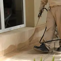 General pest control technician spraying exterior perimeter around a home in Seattle, WA