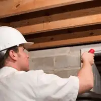 Termite inspection technician checking a basement wall and framing for termite activity in Seattle, WA